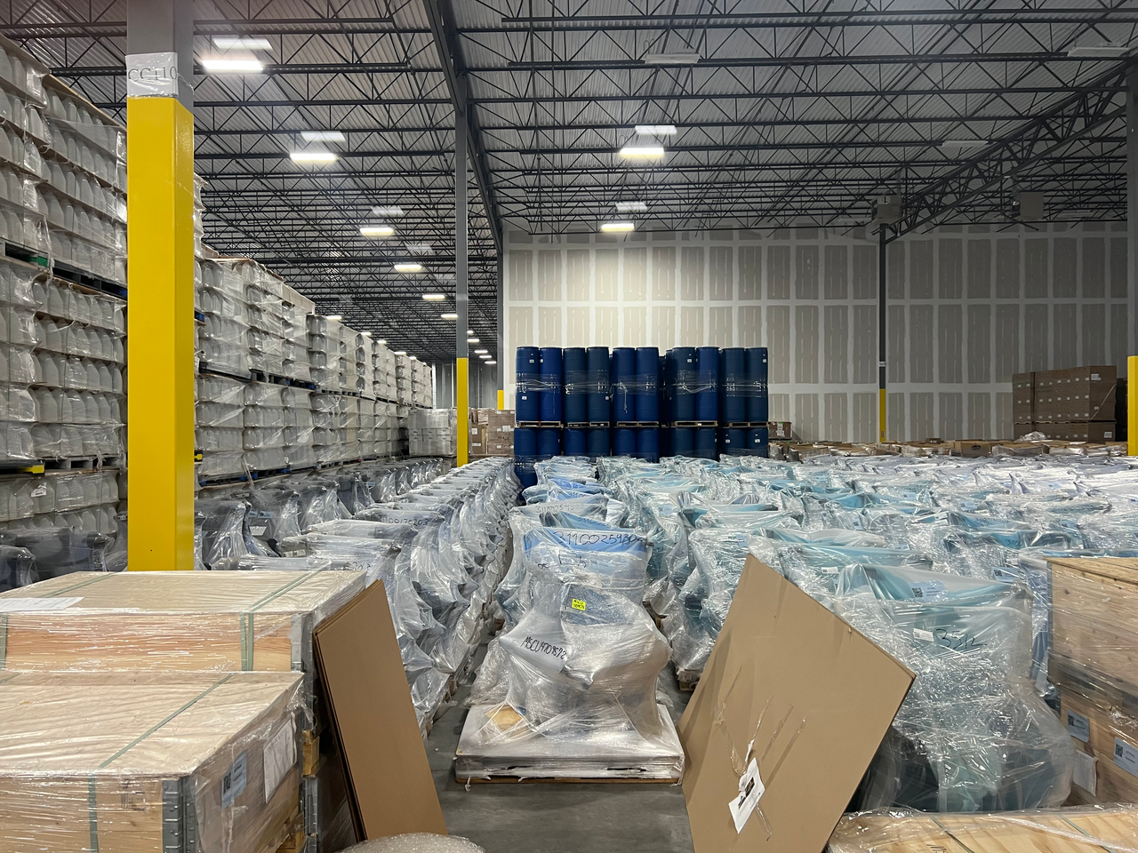 services-01 Large industrial warehouse filled with stacked goods wrapped in plastic for storage.