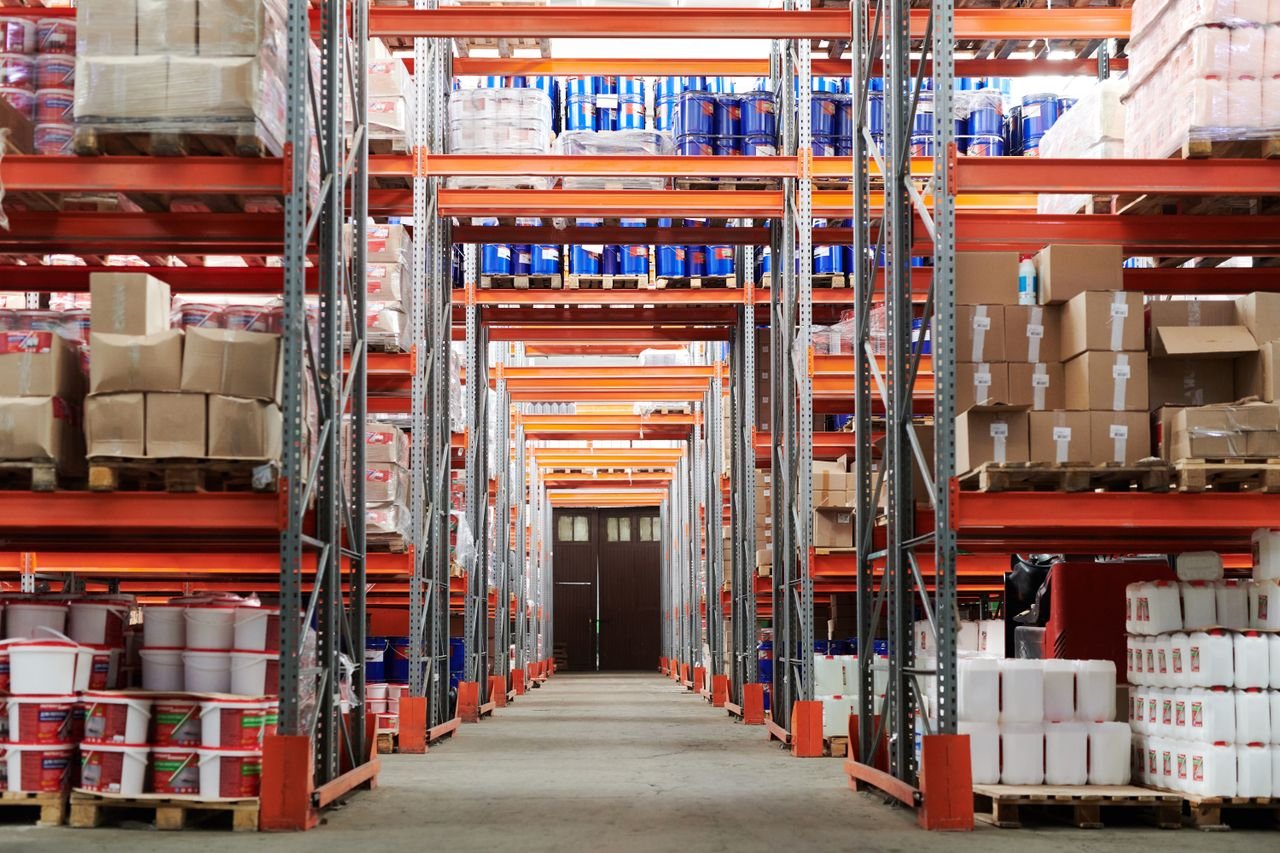 our-journey-03 Wide angle view of a warehouse with stocked shelves and boxes.