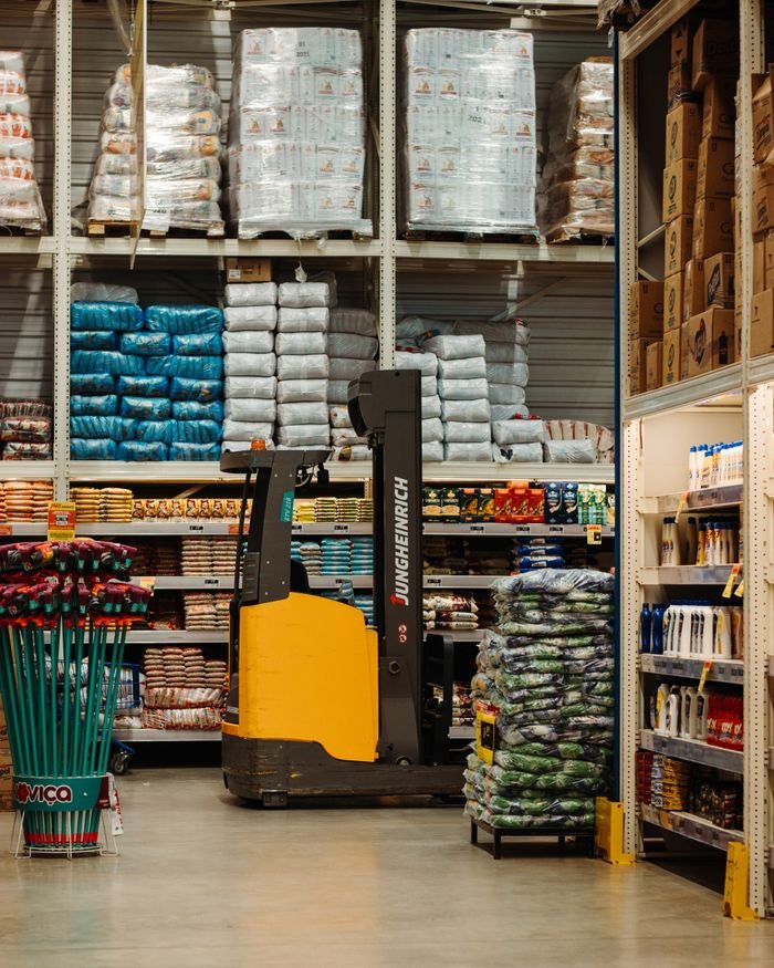 our-journey-01 A warehouse with stacked goods, shelves, and a forklift in Brazil.